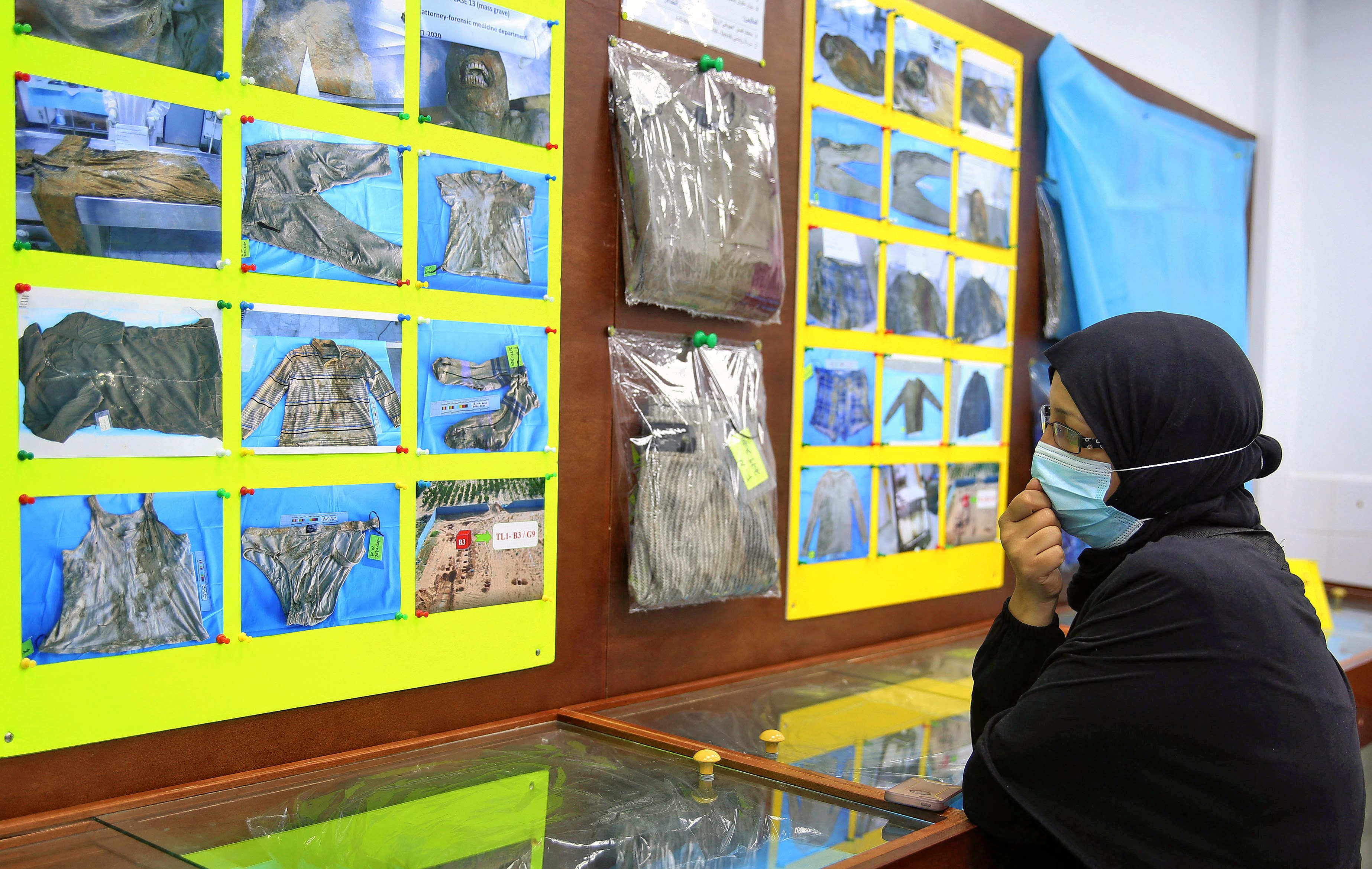 تنظر امرأة ليبية إلى ممتلكات ضحايا تم العثور عليهم في مقابر جماعية قرب ترهونة. دعت هيومن رايتس ووتش الحكومة الليبية لفتح تحقيق لتحديد هوية مئات المفقودين في المنطقة. 11 يناير 2021، تصوير: وكالة الأنباء الفرنسية