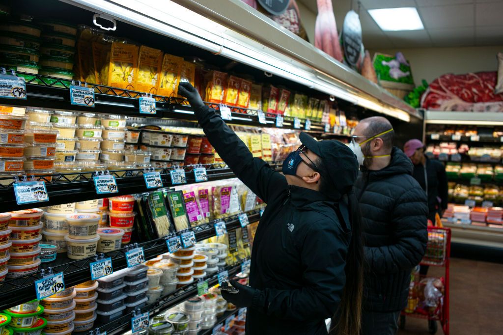 BROOKLYN, NEW YORK - MARCH 28: Shoppers wearing a surgical masks look at a prepared meals at a Trader Joes in Brooklyn, New York on March 28, 2020. The store lets in a minimum amount of shoppers at one time due to the spreading coronavirus. Trader Joes is an American chain of grocery stores headquartered in Monrovia, California. (Photo by Robert Nickelsberg/Getty Images)